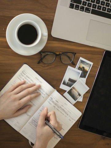 person holding ballpoint pen writing on notebook